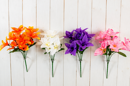 Four artificial ginger lily flower bushes in orange, white, purple and pink, featuring decorative lily-shaped blooms, green foliage and bundled stems, displayed against white wooden panelling.