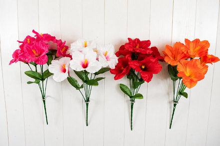 Four artificial hibiscus flower arrangements in bright pink, white with pink centres, red and orange, featuring tropical-style blooms with yellow stamens, green foliage and bundled stems against white wooden panelling.